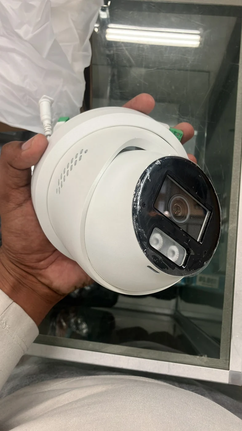 A real white 6 MP turret security camera held in hand